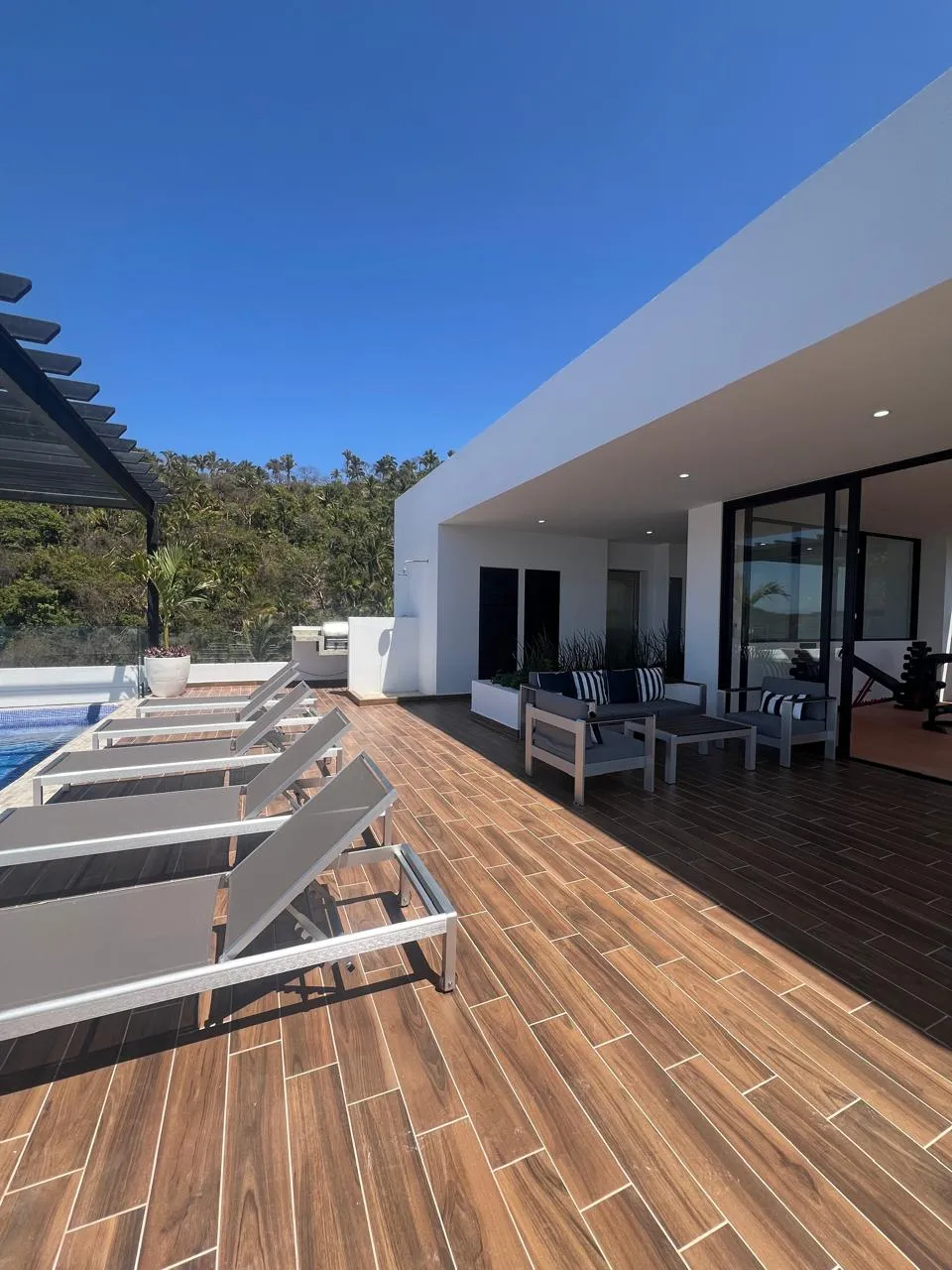 Casa blanca con terraza de deck y camastros